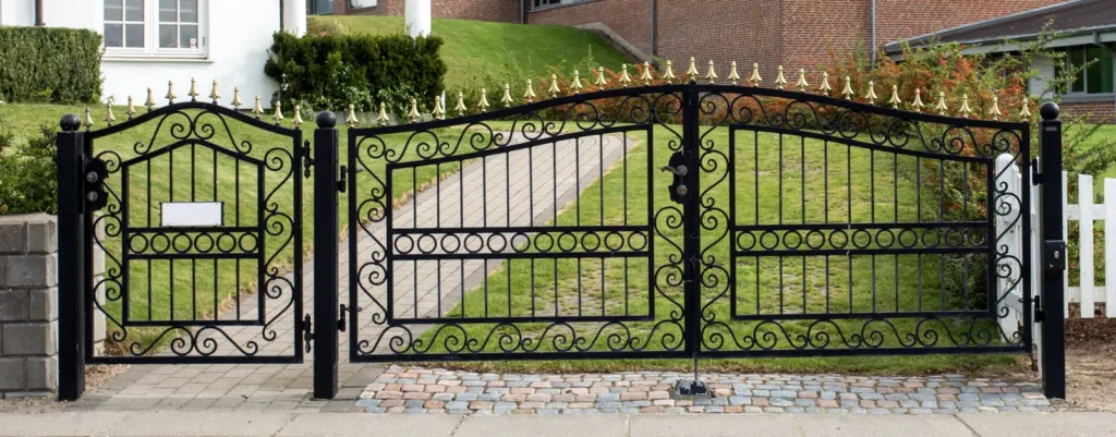 Arched black iron double gate with a matching pedestrian gate
