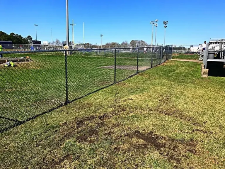 Black vinyl-coated chain link fence along a sports field