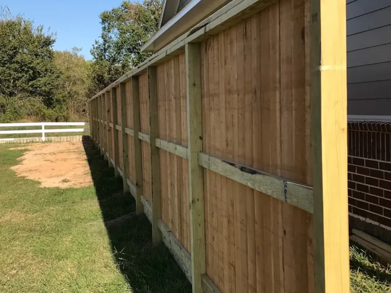 Back side of a framed cedar fence showing posts, rails and trim