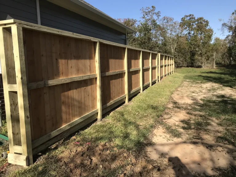 Framed wood privacy fence with top cap and trim boards during construction