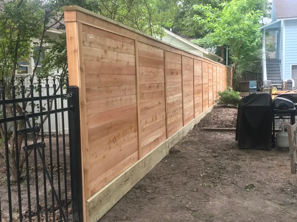 Horizontal cedar fence with a black iron gate in a backyard
