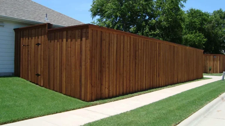 Stained cedar privacy fence with a top cap running along a neighborhood sidewalk